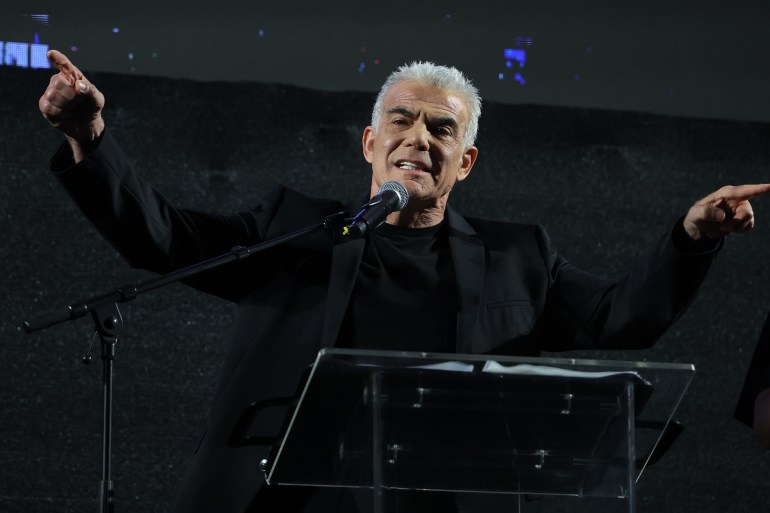 a man in black speaks with his arms out