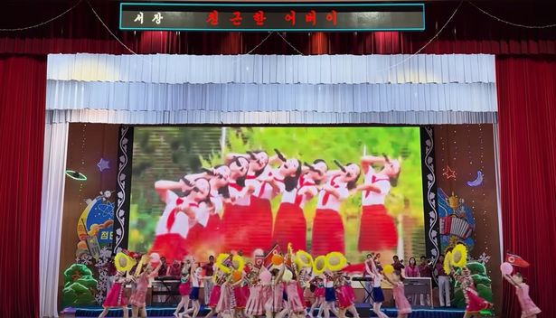 A shot of school children performing on stage for tourists in North Korea