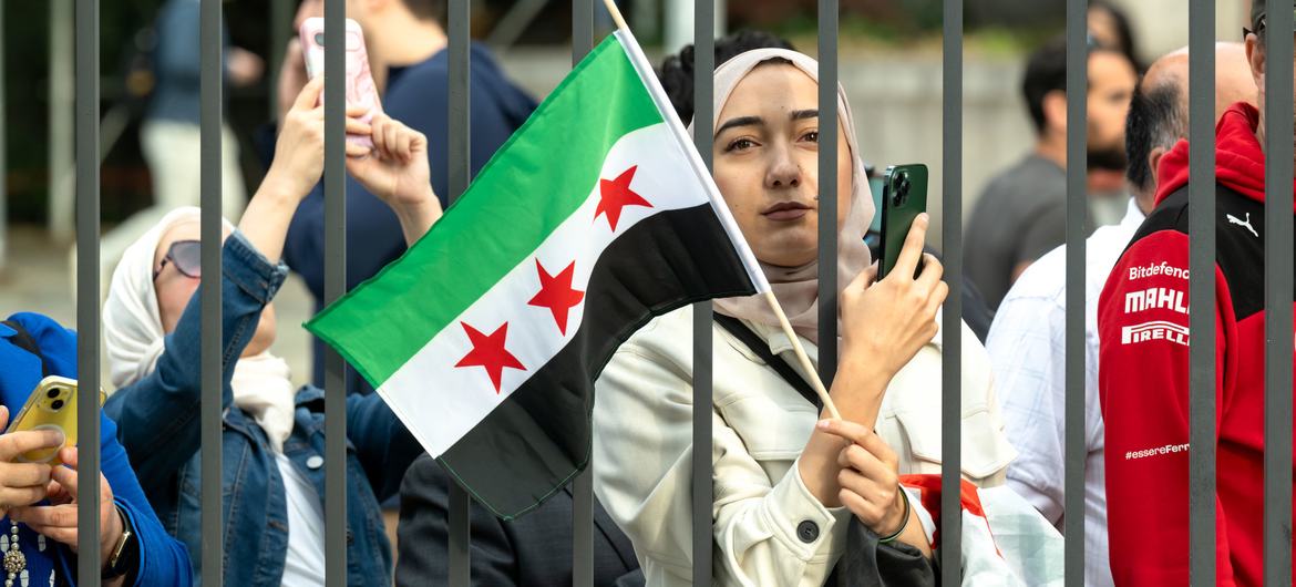 A woman holds the new Syrian flag outside UN Headquarters in New York.