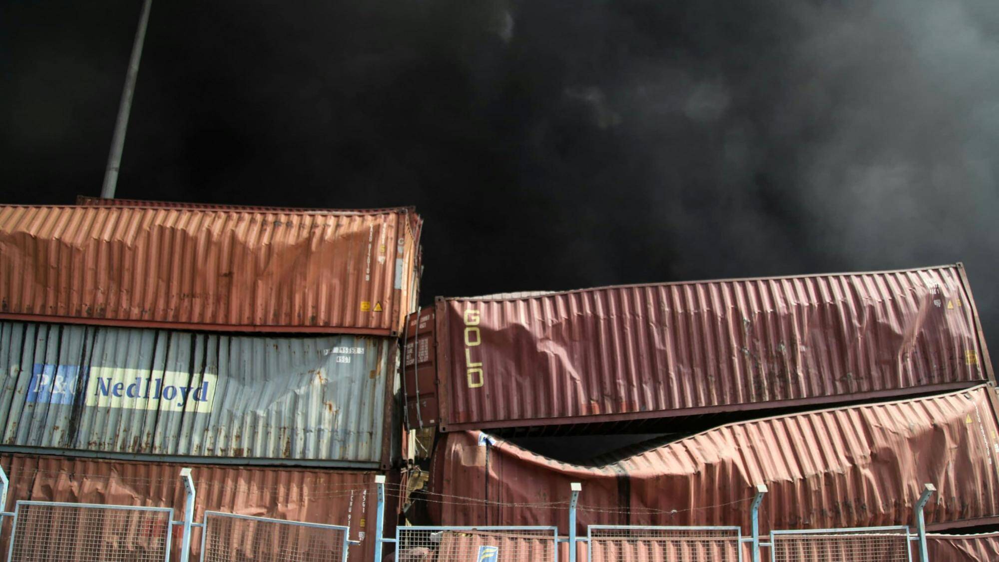 De la fumée noire s'élève derrière les conteneurs endommagés à la suite d'une explosion au quai du port Shahid Rajaee, au sud-ouest de Bandar Abbas, dans la province iranienne d'Hormozgan, le 26 avril 2025. — © MOHAMMAD RASOLE MORADI / AFP