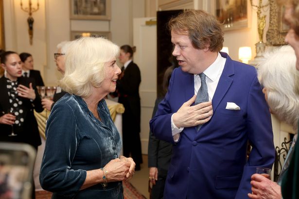 Queen Camilla speaks to her son Tom Parker Bowles during a reception to mark the launch of the Queen's reading room medal at Clarence House on March 25, 2025 in London,