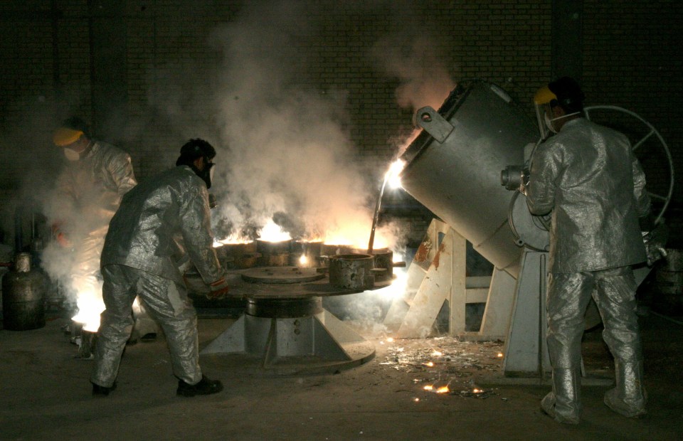 Workers in protective gear pour molten metal at an industrial plant.