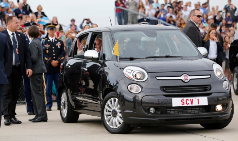Pope Francis waves as he is driven away in a Fiat 500 model after arriving in the United States at Joint Base Andrews outside Washington