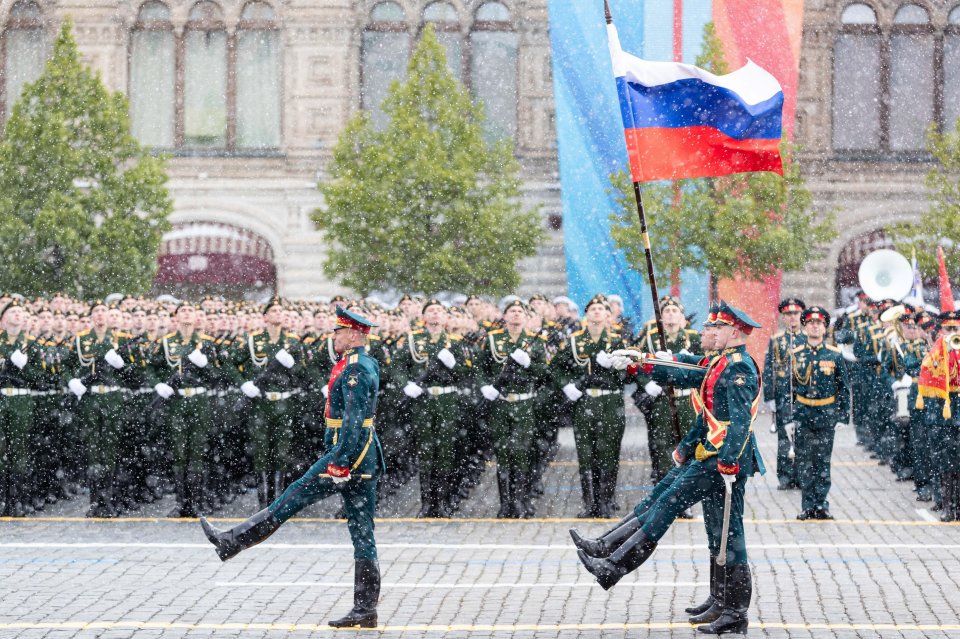 Russian honor guard soldiers marching with the national flag during a Victory Day military parade in Moscow.