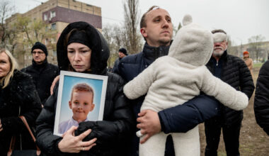 Parents hold portrait of their son killed in Russian missile strike near a makeshift memorial on a playground.