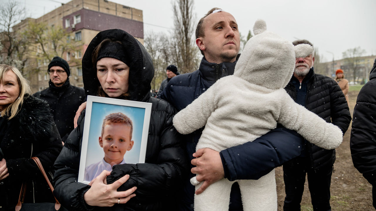 Parents hold portrait of their son killed in Russian missile strike near a makeshift memorial on a playground.