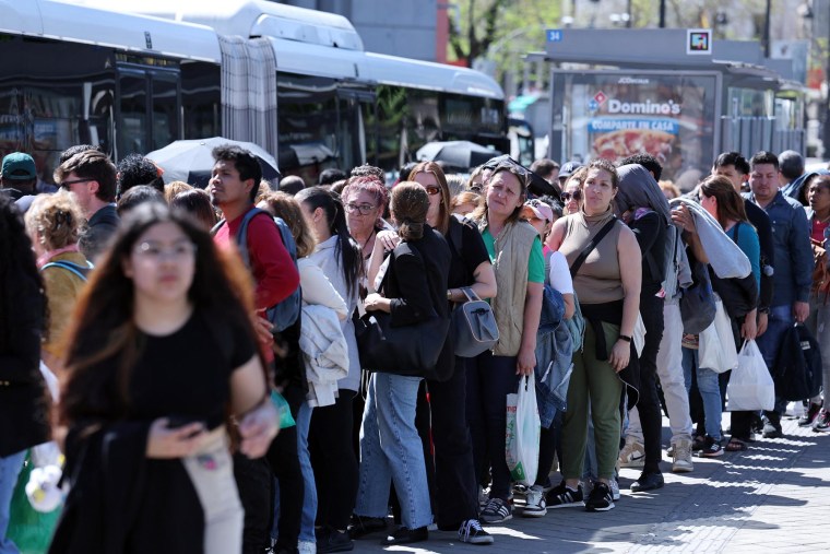 Travelers line up at a bus stop in downtown Madrid 