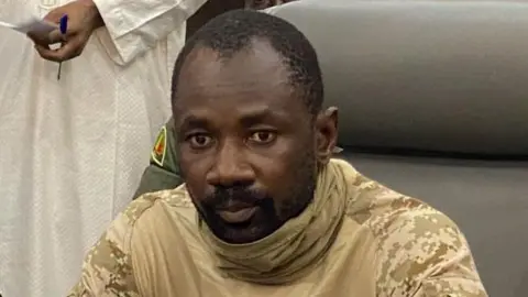 AFP Gen Assimi Goïta wearing camouflage sits in a grey chair before microphones