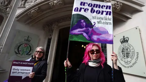 EPA Woman with pink dyed hair hols up a banner saying 'woman are born' outside the supreme court door