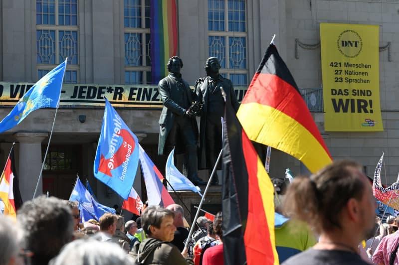 People wave flags in front of the Goethe-Schiller monument in Weimar during the demonstration "Together for Germany" in Weimar. Heiko Rebsch/dpa
