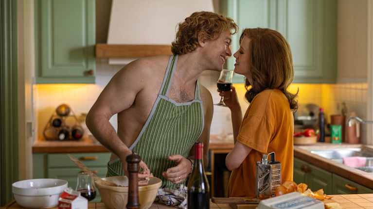 Jan Stenbeck (Jakob Oftebro) lagar köttbullar och kysser hustrun Merrill (Zoe Boyle) som har ett rödvinsglas i handen.