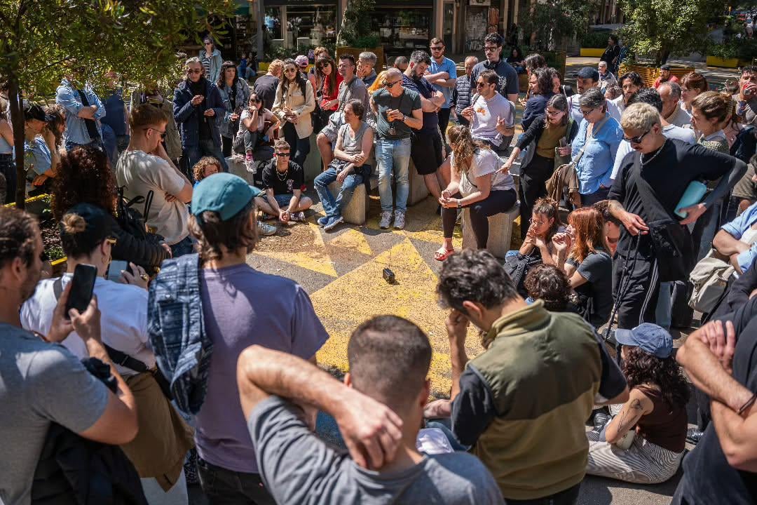 A large group of people in Barcelona sharing a single radio to stay informed during the power outage.