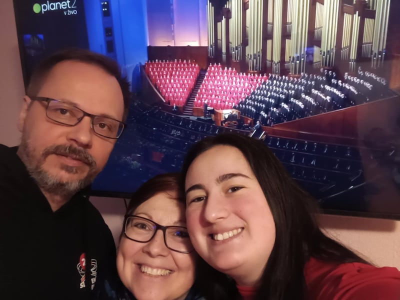 Three people take a selfie in front of their TV as they watch a general conference broadcast in Ruše, Slovenia.