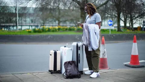 PA Media Stranded passenger waits at a roundabout near Heathrow Airport