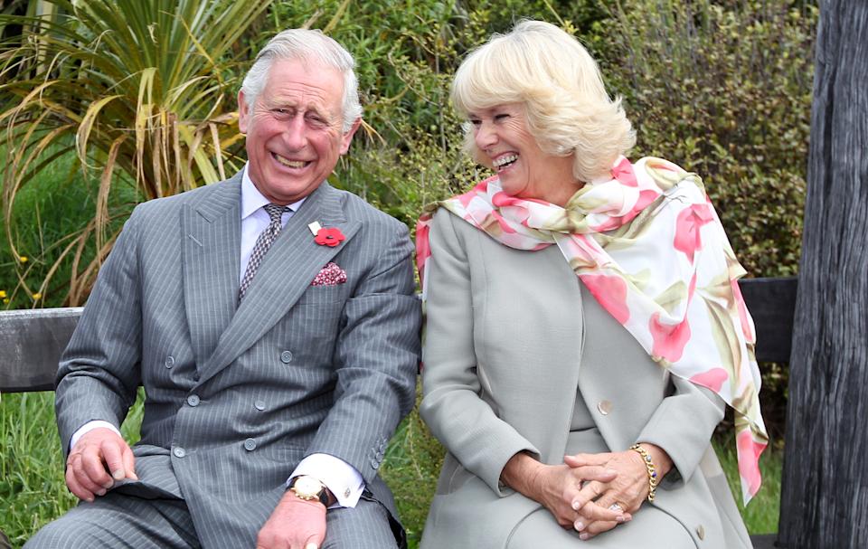 King Charles and Queen Camilla laughing on a bench