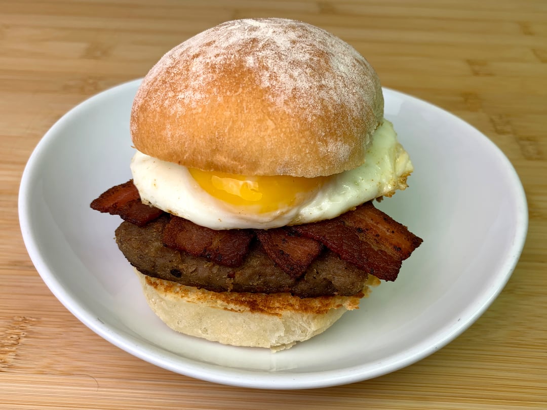 Toasted roll with steak square, smoked bacon and egg