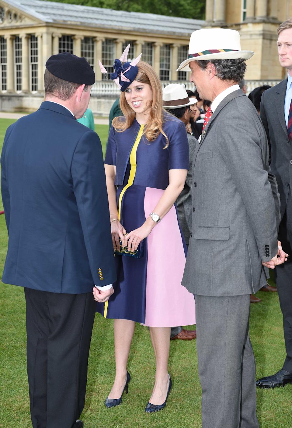 Princess Beatrice speaking to men at a Buckingham Palace garden party in 2016