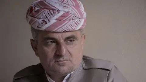 Phil Caller A middle-aged man in a head scarf and brown jacket stares contemplatively