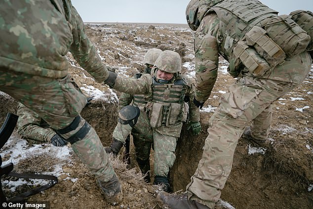 Britain has become a bigger target after having taken a more prominent leadership role in support of Ukrainian troops over the last months, analysts have claimed. Pictured are Romanian and British soldiers training in trenches on February 17 in Smardan, Romania