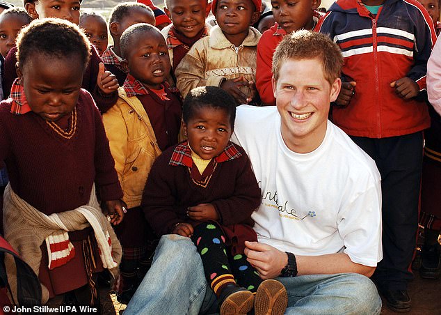 Twenty-two-year-old Prince Harry wearing a shirt with the Sentebale logo with children from the Good Shepherd Centre, which helps mothers living in poverty or with illness, on a visit to Lesotho in 2006