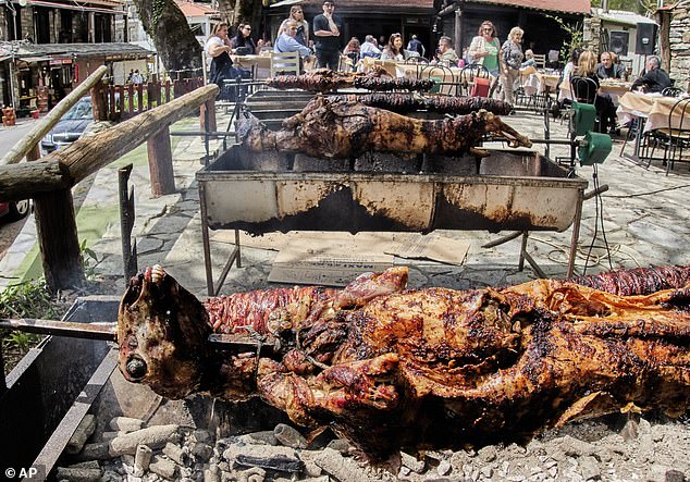 Traditional Greek Easter lambs that were slaughtered the evening before roll on a skewer and wait for customers in a village high above the city of Volos