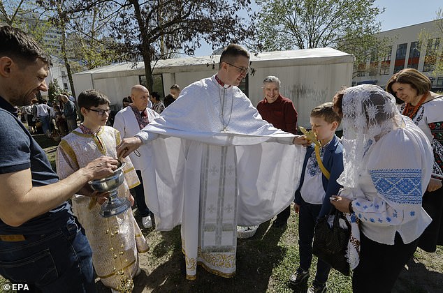 A Ukrainian priest blesses believers and their baskets containing painted eggs and kulichi, a traditional Easter cake, during Easter Mass at the temporary Saints Boris and Glib Greek Catholic Church in Kyiv, Ukraine