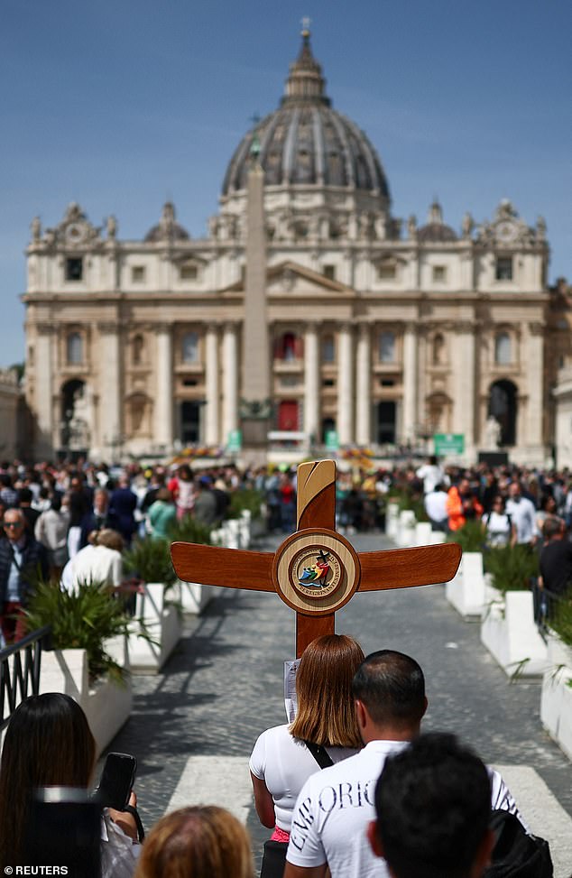 A pilgrim carries a cross near St Peter's square today after the death of Pope Francis was announced by the Vatican