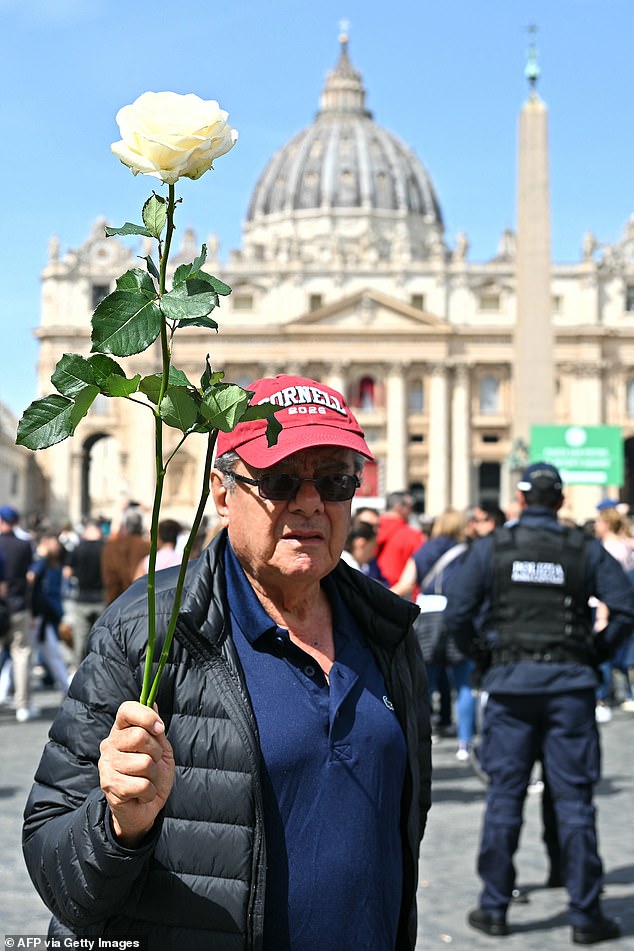 A man holding a white rose stands at St Peter's square following the death of Pope Francis in the Vatican on April 21, 2025