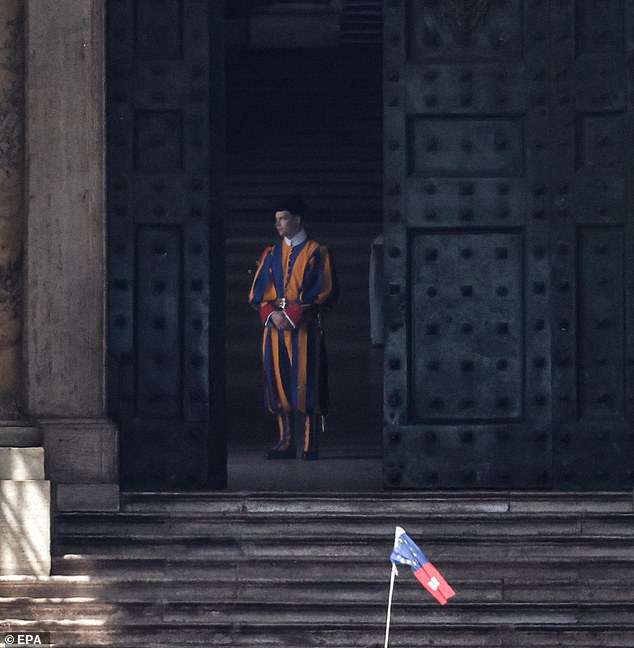 A Swiss Guard stands on duty at an entrance to the St. Peter's Basilica today following the death of Pope Francis