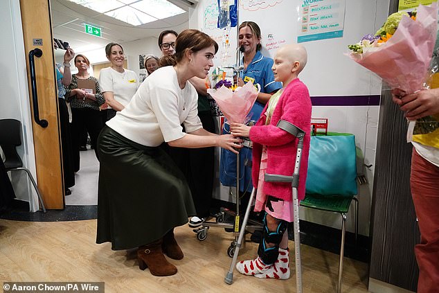 Princess Eugenie receives flowers from a young cancer patient, Belle Tucker, during a visit to the Teenage Cancer Trust unit at University College Hospital, London