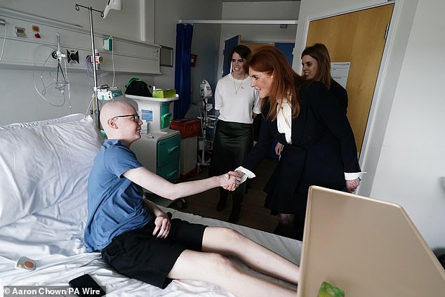 Fergie is pictured shaking hands with patient Matthew Pegg inside the hospital with her daughters