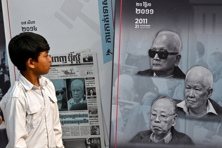 This photo taken on March 24, 2025, shows a student looking at a poster of former Khmer Rouge leaders during an outreach programme at a school in Phnom Srok district in Banteay Meanchey province. Sheltering in the shade of a bus repurposed into a mobile museum, Mean Loeuy tells a group of children about the hell he went through in a Khmer Rouge labour camp. (Photo by TANG CHHIN Sothy / AFP) / TO GO WITH 'CAMBODIA-KHMER ROUGE-HISTORY-ANNIVERSARY-EDUCATION,REPORTAGE' BY ALEXIS HONTANG AND SUY SE