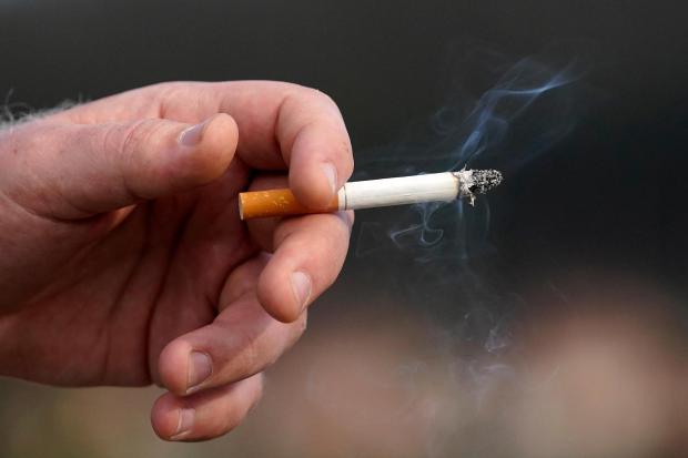 FILE - A man holds a lit cigarette while smoking in San Francisco, Wednesday, Dec. 2, 2020. (AP Photo/Jeff Chiu, File)