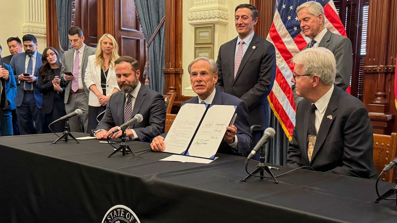 Texas Gov. Greg Abbott, center, holds a newly signed bill creating the Texas Regulatory Efficiency Office during a ceremony inside the state Capitol on Wednesday, April 23, 2025, in Austin, Texas. (AP Photo/Nadia Lathan)