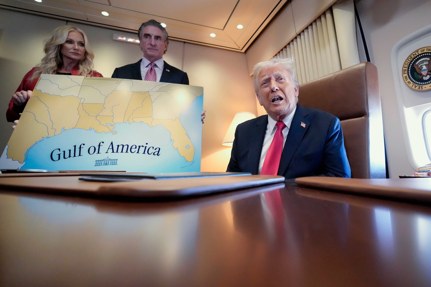 President Donald Trump, on right, accompanied by Interior Secretary Doug Burgum and Burgum's wife Kathryn Burgum, who are holding a map of the 'Gulf of America,' aboard Air Force One.