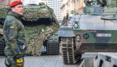 German army, NATO response force or North Atlantic Treaty Organization armored crawler tanks and other military vehicles on the road of the city with soldiers.