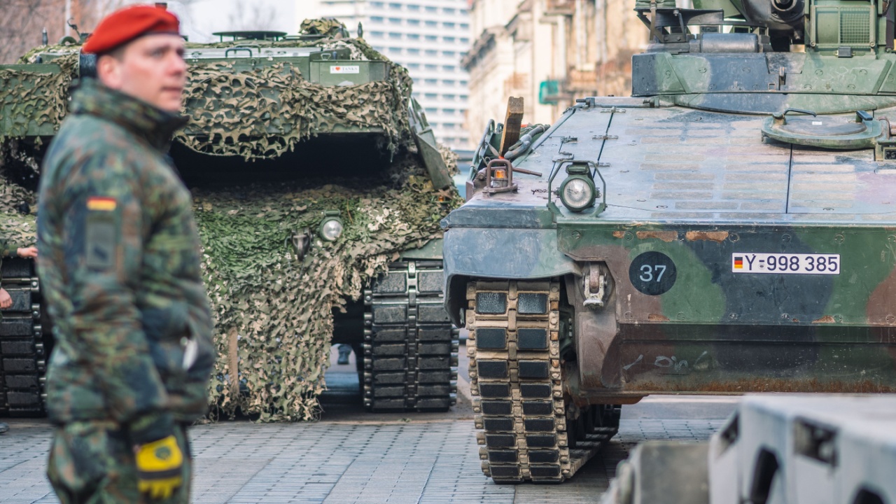 German army, NATO response force or North Atlantic Treaty Organization armored crawler tanks and other military vehicles on the road of the city with soldiers.