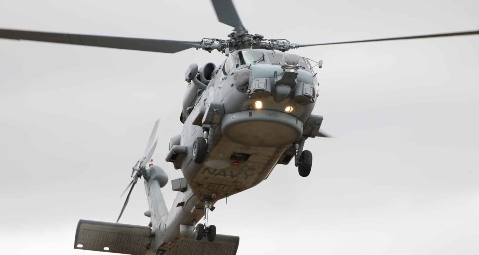 An MH-60R of the Royal Australian Navy, one of its 23 currently operational Romeos, flies overhead.