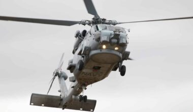 An MH-60R of the Royal Australian Navy, one of its 23 currently operational Romeos, flies overhead.
