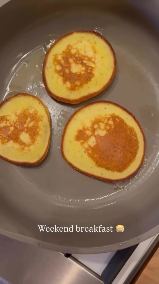 Three pancakes cooking in a pan.