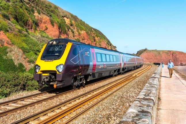 PTPB0F DAWLISH, DEVON, UK - 3OCT2018: Arriva Cross Country Class 220 High Speed Train travelling north along the sea wall at Dawlish. The Langstone Rock can