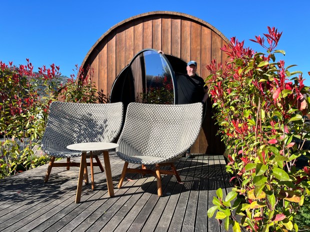 A man stands at the patio door of a giant wine barrel