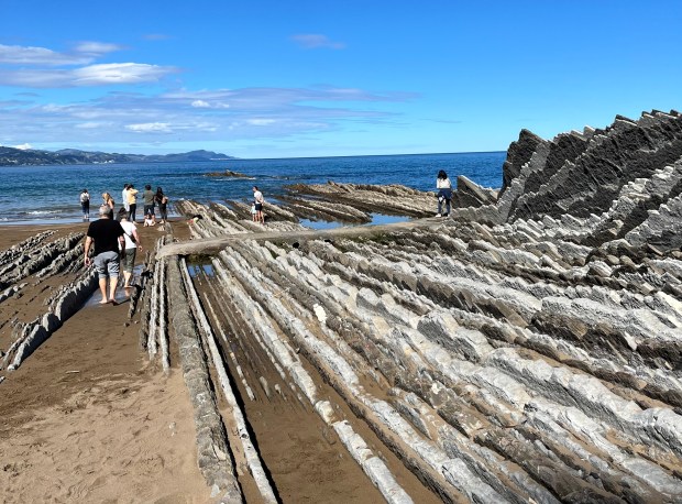 A beach with striped rock fixtures jutting up out of the sea