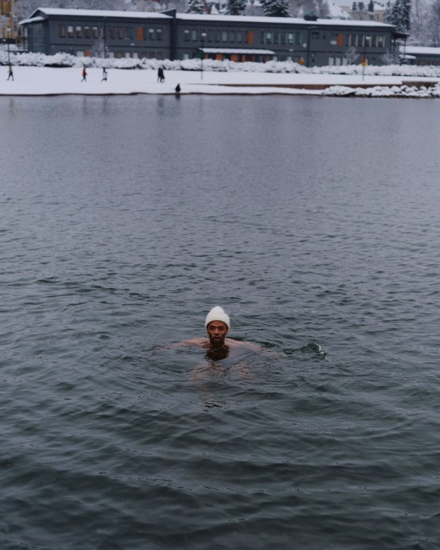 Jani Toivola swims in the ocean in Helsinki, Finland on Feb. 19, 2023. ​​Toivola, who lives in Helsinki with his husband and daughter, became the first Black member of Finland's Parliament in 2011. (Jake Michaels/The New York Times)