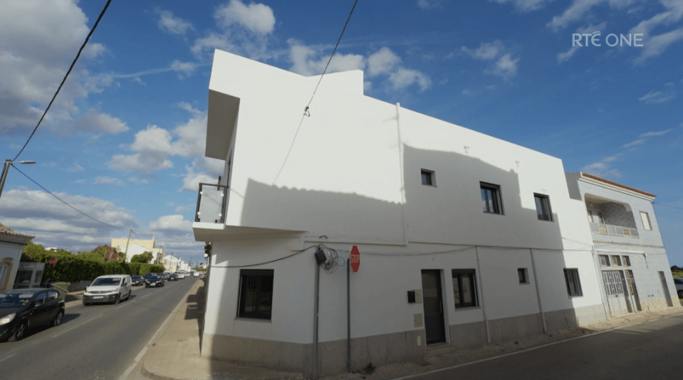 White building on a street with cars.