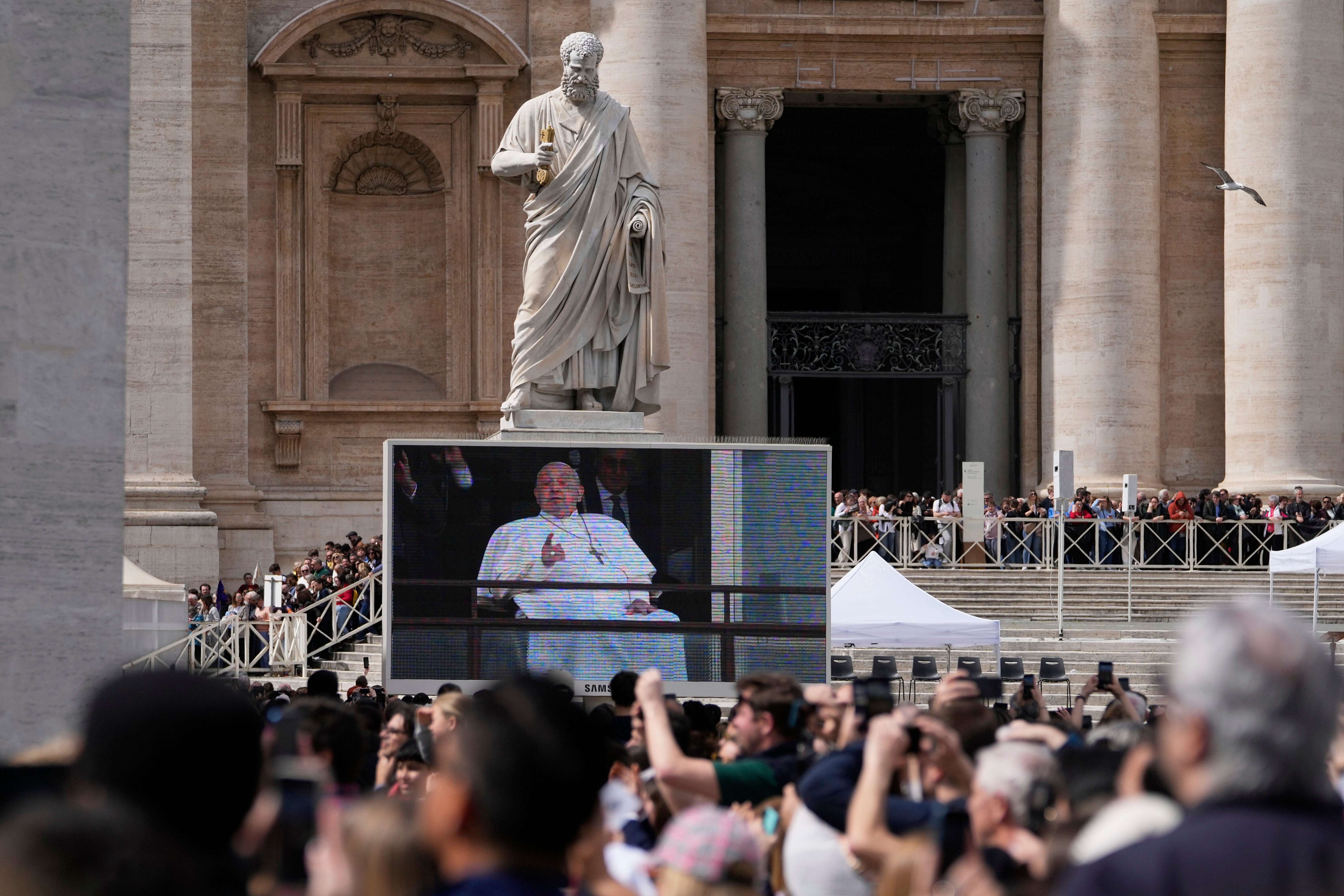 Faithful and pilgrims gather in St. Peter's Square at The Vatican to follow on giant screens a live broadcast from Rome's Agostino Gemelli Polyclinic on March 23, where Pope Francis made his first public appearance since he was hospitalised with bilateral pneumonia.