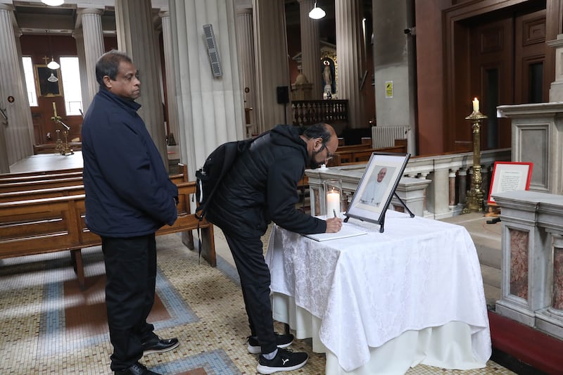 Francis Xavier Sedona and Camilo Fernandez paying their respects in St Mary's Pro Cathedral in Dublin on Tuesday morning at the book of condolence for Pope Francis. Photograph: John Mc Elroy.