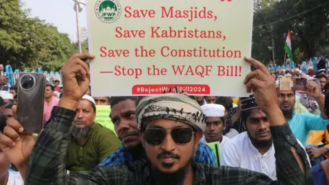 Getty Images A man holds up a placard opposing the new Waqf bill, surrounded by more protesters