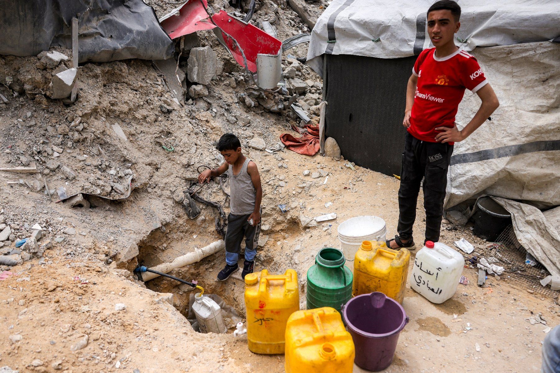 Des enfants gazaouis remplissent des bidons d'eau à une canalisation, à Beit Lahia, dans le nord de la bande de Gaza, le 24 avril 2025