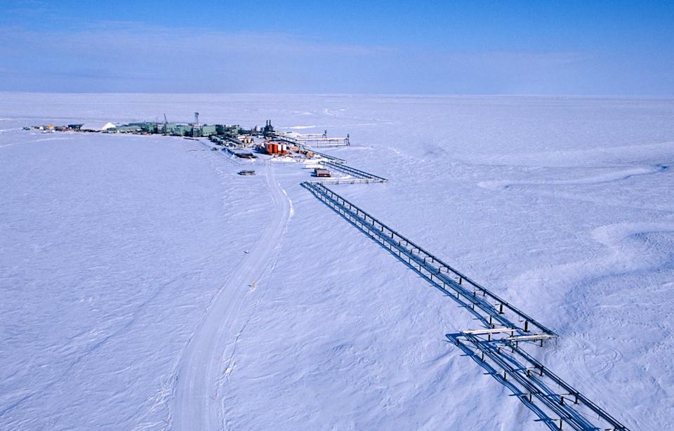 A group of buildings and pipes sit atop a snow-covered landscape.